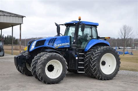Zdjęcie ciągników Kirowiec K700 i New Holland T8 350 połączonych liną, na utwardzonej drodze