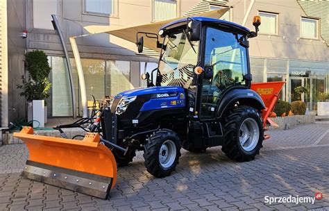 zdjęcie traktorka z różnymi akcesoriami, np. pługiem śnieżnym, przyczepką