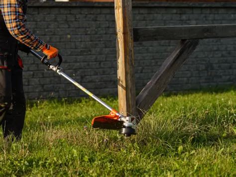 Zdjęcie przedstawiające osobę obsługującą kosę spalinową z przystawką glebogryzarką, ułatwiającą prace ogrodowe