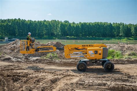 Zilustrowanie koparki JCB w charakterystycznym żółtym kolorze na tle budowy