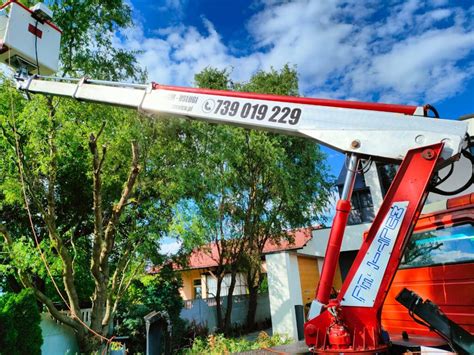 Zdjęcie koparko-ładowarki Huddig z podnośnikiem koszowym (zwyżką) w akcji przy słupie energetycznym