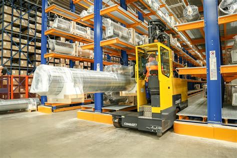 Thematic photo of a multidirectional sideloader transporting long goods in a narrow warehouse aisle