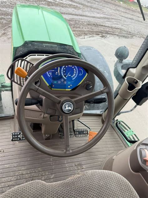 Zdjęcie kabiny ciągnika John Deere 6150R z widocznymi nowoczesnymi panelami sterowania