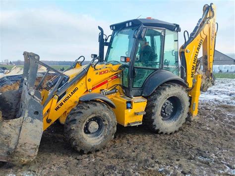 Fotografia przedstawiająca koparko-ładowarkę teleskopową w akcji na placu budowy.