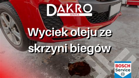 Mechanik samochodowy oceniający wyciek oleju ze skrzyni biegów, otoczony narzędziami i podnośnikiem