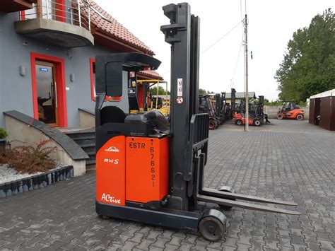 Wózek widłowy reach truck podnoszący paletę na wysokim regale