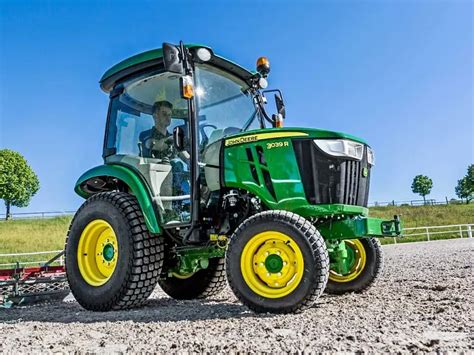 Zdjęcie kompaktowego ciągnika John Deere pracującego na terenie osiedlowym