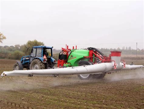 Rolnik przygotowujący ciecz roboczą w opryskiwaczu, dodający mocznik