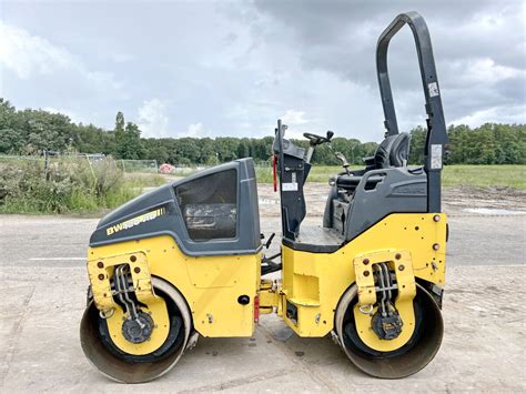 Schematyczna ilustracja lekkiego walca tandemowego Bomag BW 120 w akcji na placu budowy.