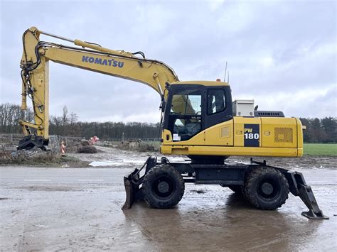 Operator koparki Komatsu PW180 w kasku i obuwiu ochronnym
