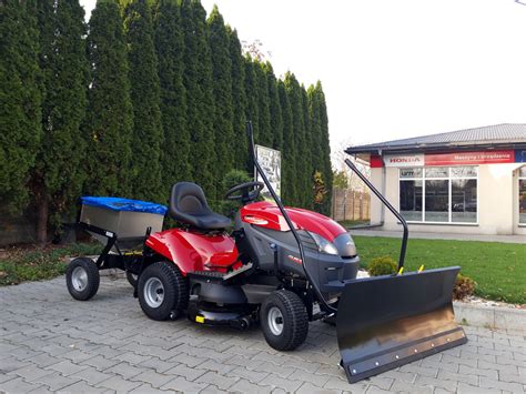 Schemat budowy traktora kosiarki Mountfield MTF98HB z zaznaczonymi kluczowymi elementami: silnik, agregat tnący, kosz na trawę, reflektory.