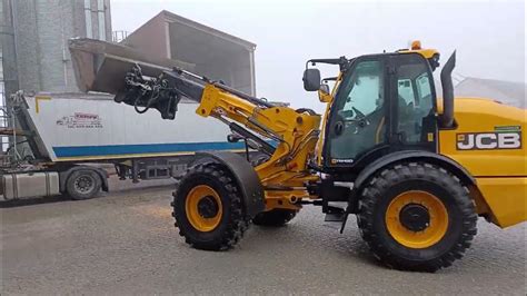Zilustruj ładowarkę przegubowo-teleskopową JCB serii TM podczas pracy w gospodarstwie