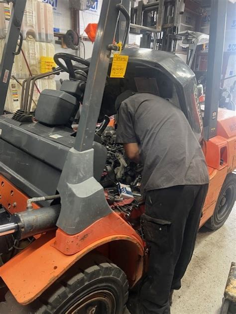 Photo of a service technician inspecting an LPG forklift engine