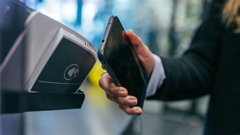 Osoba dokonująca płatności zbliżeniowej smartfonem przy terminalu mPOS
