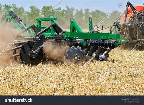 Photo of a disc harrow with a cutting roller working in a field after corn harvest