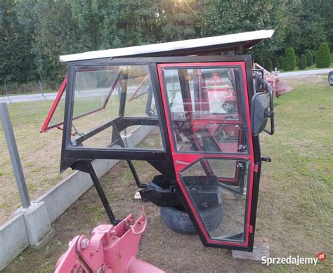 Duża, przeszklona kabina minikoparki z widokiem na otoczenie i dwuczęściową szybą przednią.
