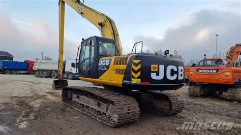 Zdjęcie koparki JCB JS 220 LC pracującej przy budowie drogi, wykonującej niwelację terenu