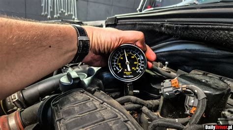 Zdjęcie mechanika wykonującego pomiar kompresji silnika ciągnika