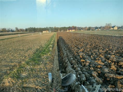 Zalane pole uprawne z ciągnikiem rolniczym w błocie