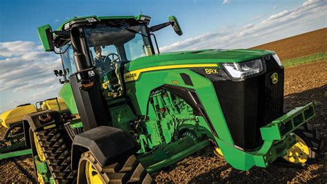 A John Deere 8RX tractor on tracks in a field, demonstrating its impressive size and power.